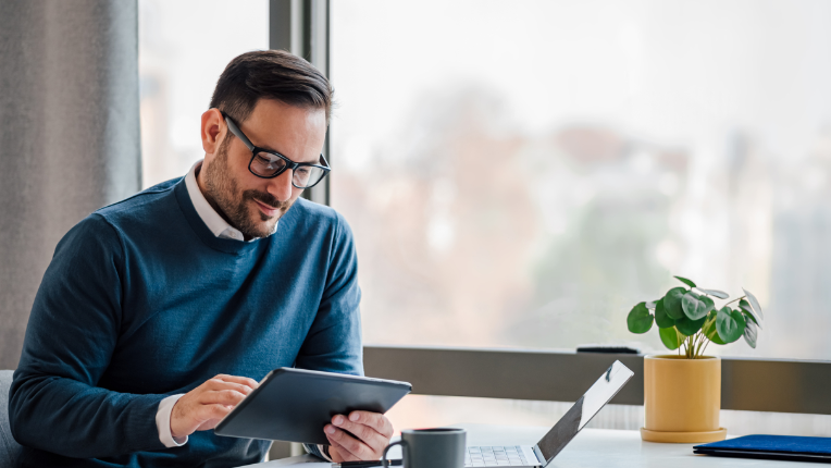 Man at table with tablet and laptop